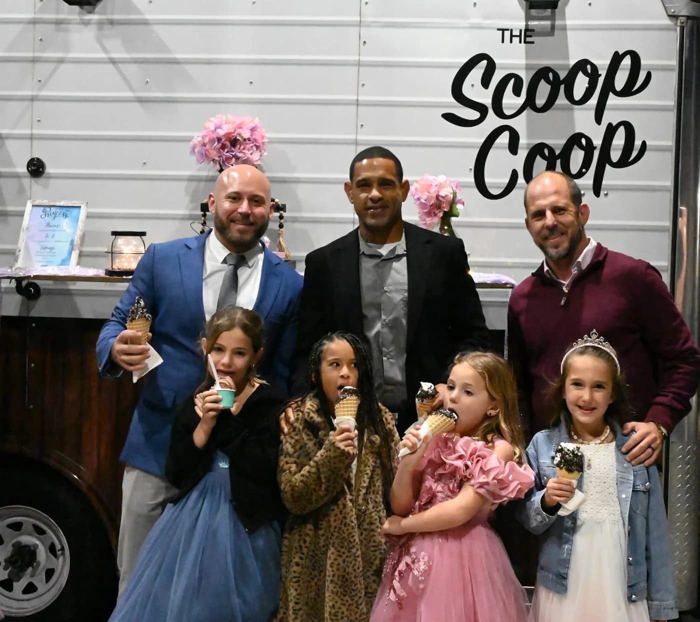 Guests in formal attire holding ice cream cones in front of The Scoop Coop truck wordmark at a milestone celebration