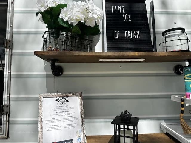 Time for Ice Cream letterboard sign with white daisies and the Scoop Coop menu card on a distressed wood shelf